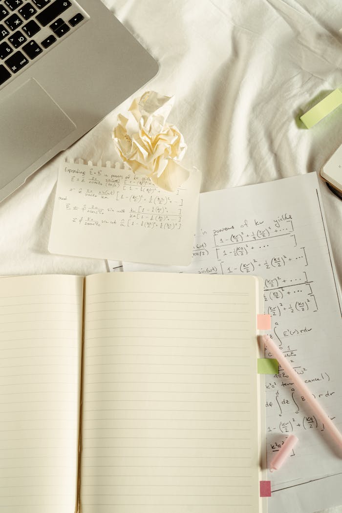 A flat lay image featuring a laptop, notebooks, and handwritten math notes, ideal for education themes.