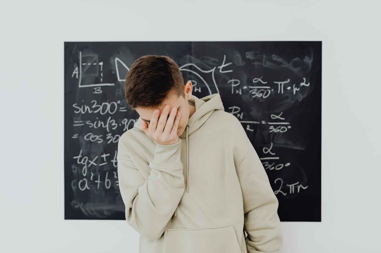 services-01 A frustrated student in a classroom standing in front of a blackboard filled with trigonometry equations.