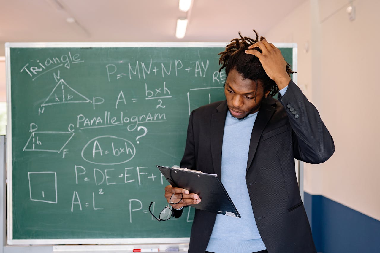 services-02 A teacher in a classroom solving math problems on a chalkboard, illustrating education and learning.
